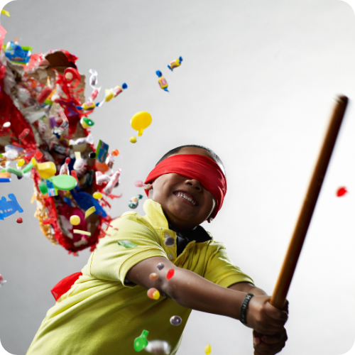 A child smashing a piñata, symbolising the joy and positive impact of ARKK’s partnerships.