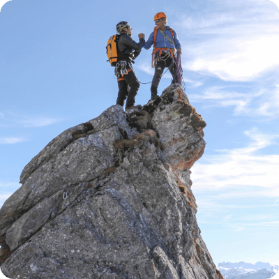 Two men standing triumphantly on top of a mountain peak, symbolising the success and clarity achieved through ARKK's digital tagging solution.